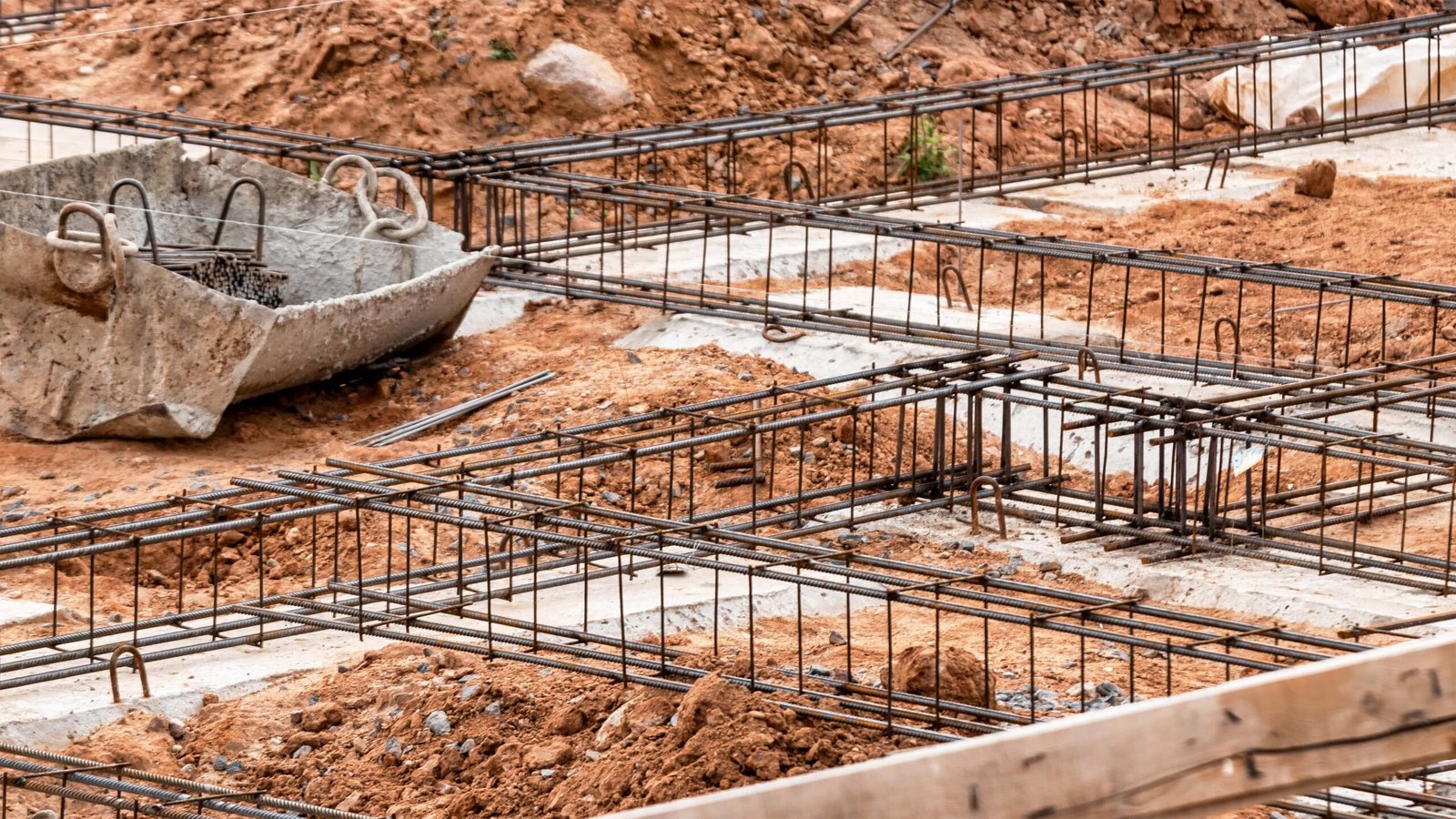 reinforced-concrete-foundation-modern-monolithic-residential-building-prepared-formwork-with-reinforcing-mesh-pouring-concrete-dirt-clay-construction-site-min reinforced-concrete-foundation-modern-monolithic-residential-building-prepared-formwork-with-reinforcing-mesh-pouring-concrete-dirt-clay-construction-site-min